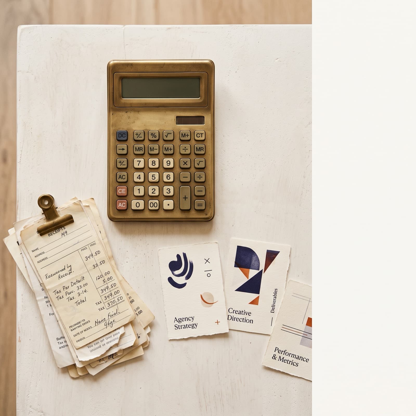 Editorial overhead flat lay of a brass calculator, stacked paper receipts, and four small on-brand product cards on a warm off-white Nordic studio surface with burnt orange and deep ink accents.