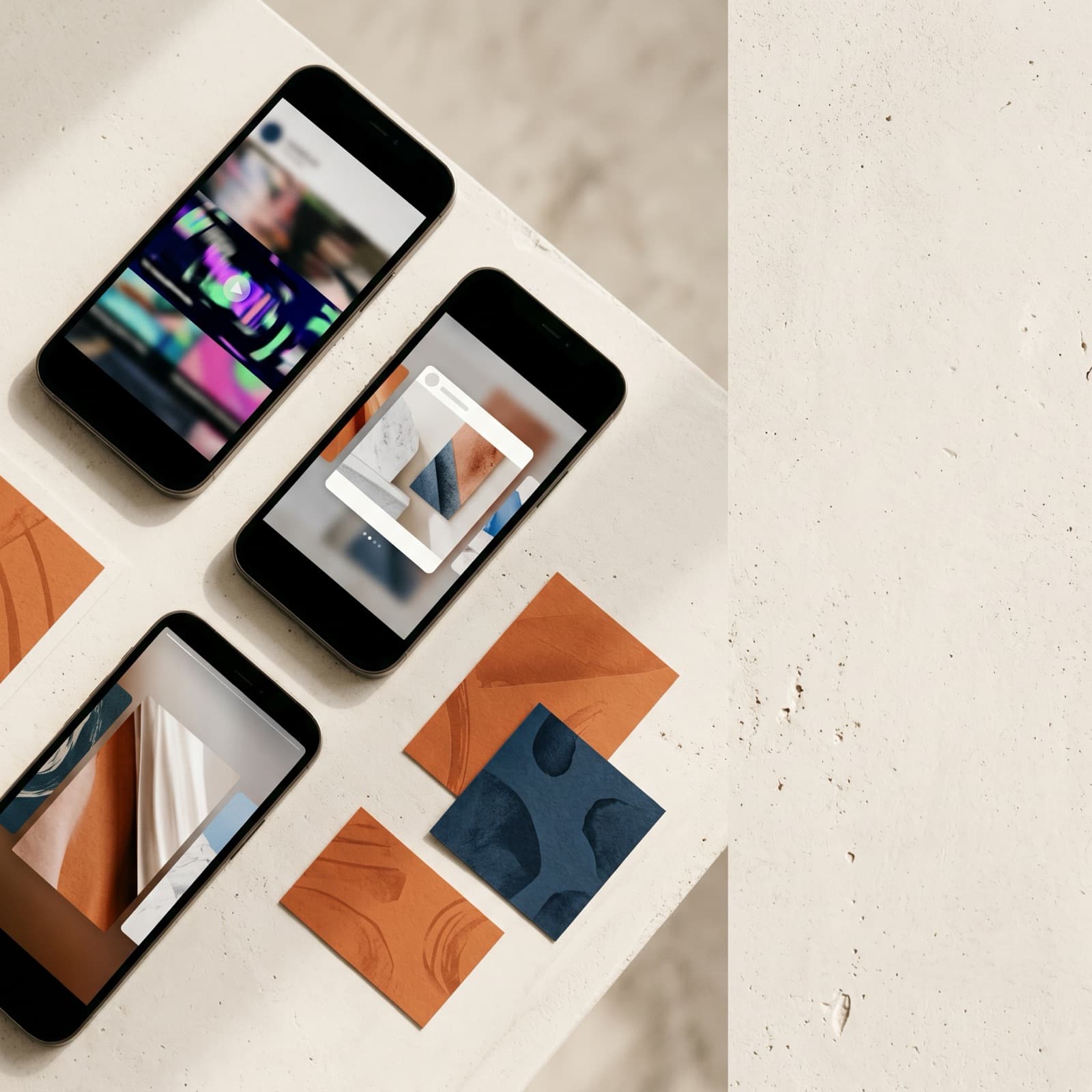 Editorial overhead flat lay of three phones showing distinct Meta ad placements with numbered paper variant cards on a warm off-white Nordic surface.