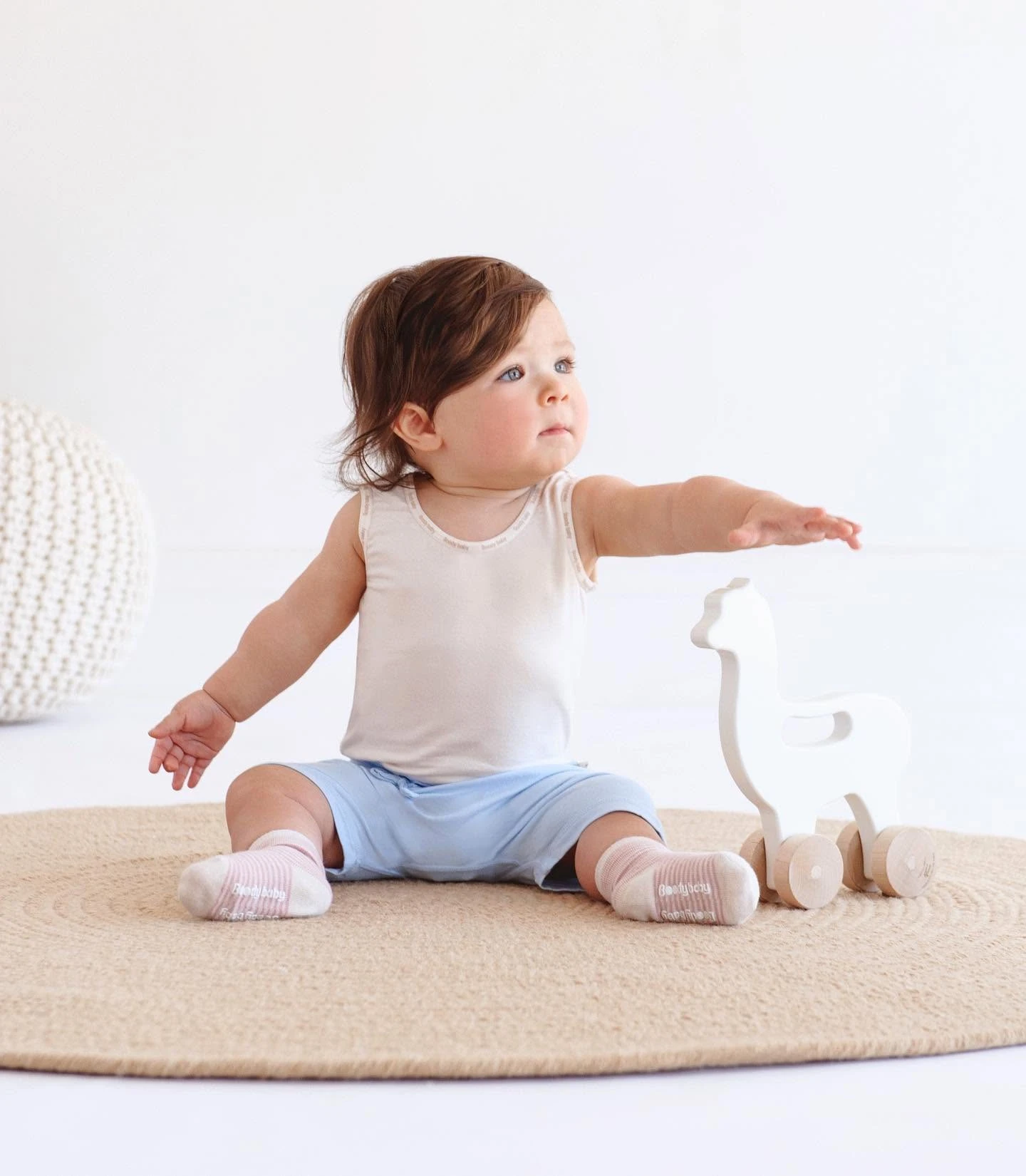 Bambui baby line: toddler in bamboo tank top and socks playing with a wooden llama